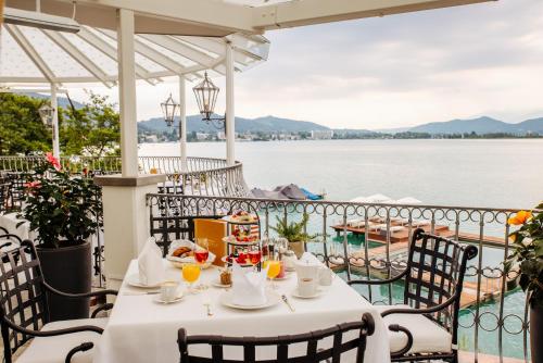 a table on a patio with a view of the water at Hotel Schloss Seefels in P&ouml;rtschach am W&ouml;rthersee