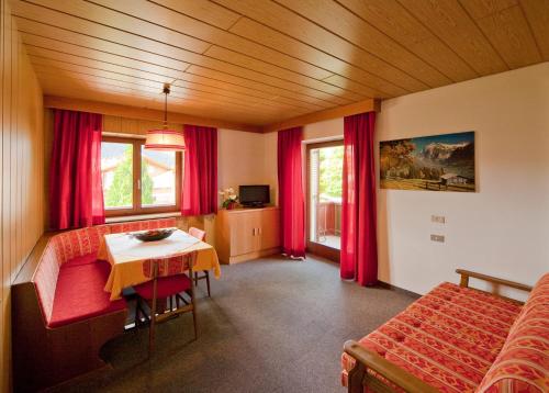 um quarto com uma mesa e uma cama e cortinas vermelhas em Residence Corones em Valdaora