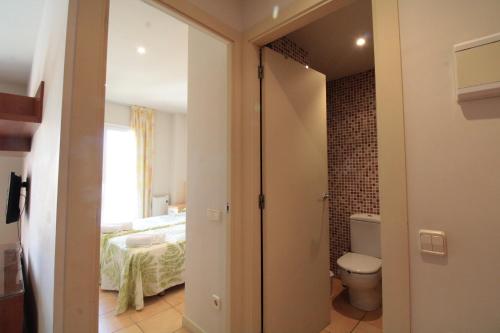 a bathroom with a toilet and a bedroom at Unio Lloret Beach in Lloret de Mar