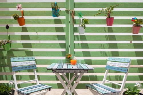 a table and two chairs next to a wall with plants at Volturno3 Suites & more in Mazara del Vallo