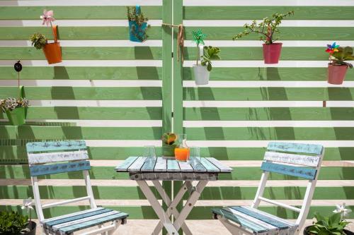 une table et deux chaises à côté d'un mur orné de plantes dans l'établissement Volturno3 Suites & more, à Mazara del Vallo