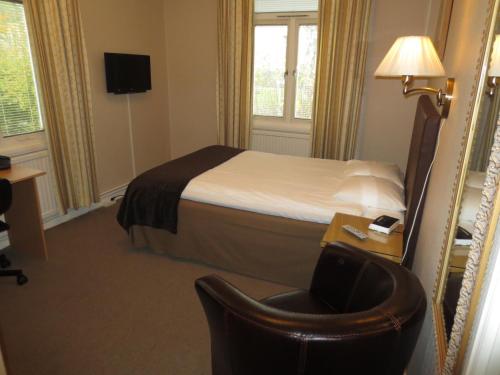 a hotel room with a bed and a chair at Hotell S:t Olof in Falköping