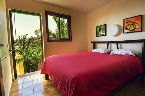 a bedroom with a red bed and a large window at Apartamentos Finca La Cruz in Tazacorte
