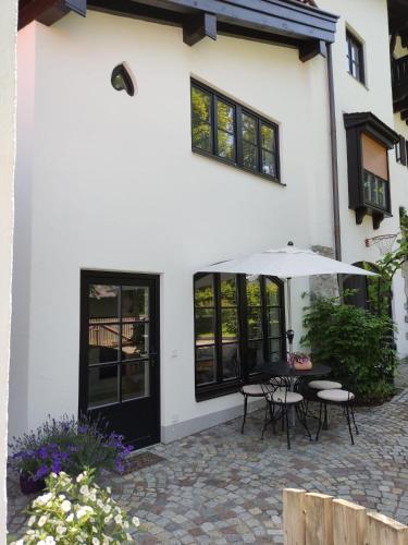 un patio con mesas y una sombrilla frente a un edificio en Ferienwohnung mit Herz, en Bad Tölz