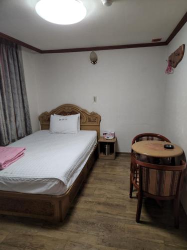 a bedroom with a bed and a wooden table at Daeho Motel in Busan