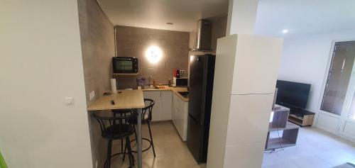 a small kitchen with a black refrigerator and a table at Studio cosy proche parc expo et aéroport cdg neuf in Villepinte