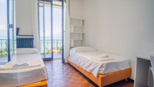 1 dormitorio con 2 camas y balcón con vistas al océano en Villa Patrizia Lake View - Italian Homing, en Desenzano del Garda