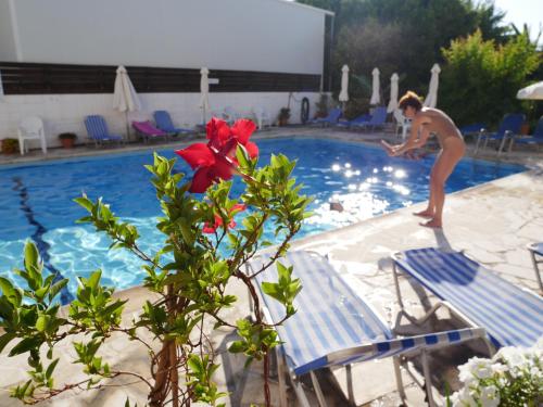 a man standing on the edge of a swimming pool at Kozis Hotel Apartments in Polis Chrysochous