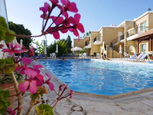 a swimming pool in a resort with pink flowers at Kozis Hotel Apartments in Polis Chrysochous