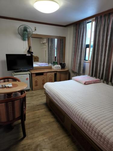 a bedroom with a bed and a table and a kitchen at Daeho Motel in Busan