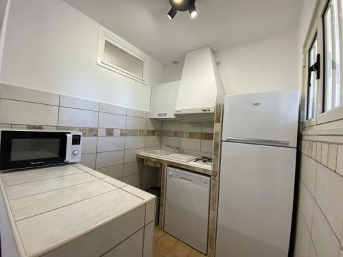 La cuisine est équipée d'un réfrigérateur blanc et d'un four micro-ondes. dans l'établissement Les Roches de Figa, à Conca