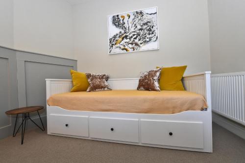 a bedroom with a white bed with yellow pillows at Lansdowne Strand in Calne