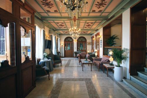 a lobby with a chandelier and couches and chairs at Syrou Melathron in Ermoupoli