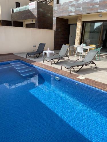 una piscina con 2 sillas y una mesa en Villa de 2022 moderna y con piscina privada, en San Pedro del Pinatar