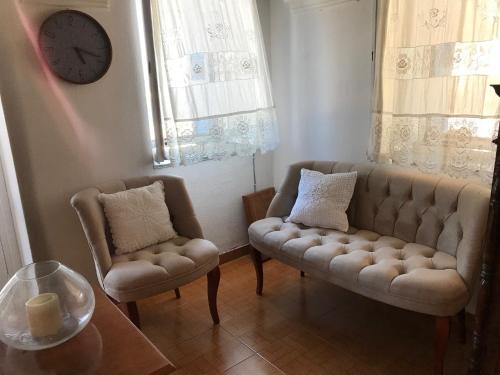 a living room with a couch and a chair and a clock at Traditional House of Diafani in Karpathos Town