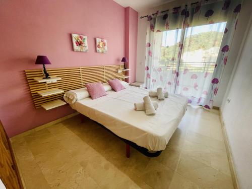 um quarto com uma cama grande com paredes cor-de-rosa e uma janela em A576 - Balcón del Mar - 2004 Finestrat s.l. em Villajoyosa