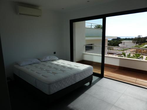 a bedroom with a bed and a large window at Résidence Les Jardins du Fort in Porticcio