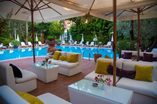 a patio with white couches and an umbrella next to a pool at Vila Belvedere in Durrës