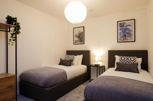 a bedroom with two beds and a chandelier at Glevum Lodge - 2 Bedroom Town Centre Apartment in Cirencester