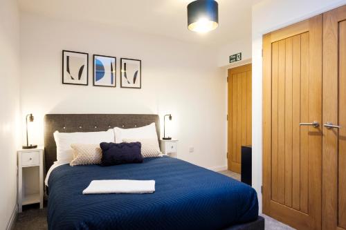 a bedroom with a blue bed with a blue blanket at Glevum Lodge - 2 Bedroom Town Centre Apartment in Cirencester