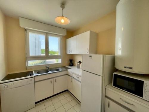 une cuisine avec un réfrigérateur blanc et une fenêtre dans l'établissement Quiberon - Appartement T2 - 50m² - Plein centre, proche plage, parking privé, loggia sud - FR-1-478-218, à Quiberon