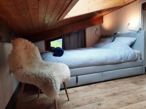 une chambre avec un lit et une chaise dedans dans l'établissement Appartement en plein centre du village (6-8 personnes), aux Contamines-Montjoie