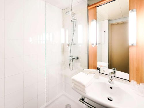 baño blanco con ducha y lavamanos en ibis Hotel Stuttgart City en Stuttgart