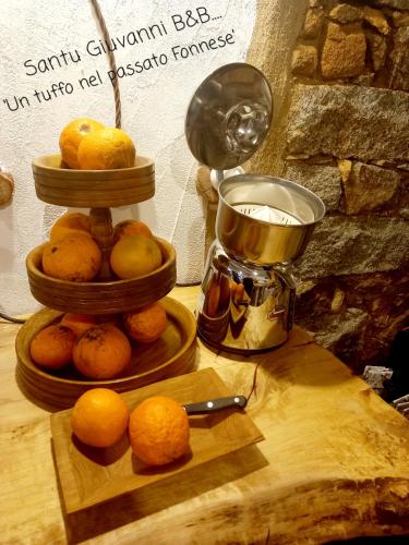 a pile of lemons on a wooden table next to a juicer at B&B Santu Giuvanni "Un tuffo nel passato Fonnese" in Fonni