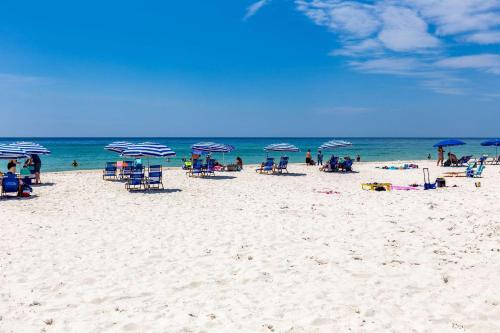 a group of people sitting on a beach with umbrellas at Sleep Inn on the Beach in Orange Beach
