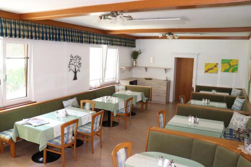 una sala da pranzo con tavoli, sedie e finestre di Pension Daniela Steiner a Podersdorf am See
