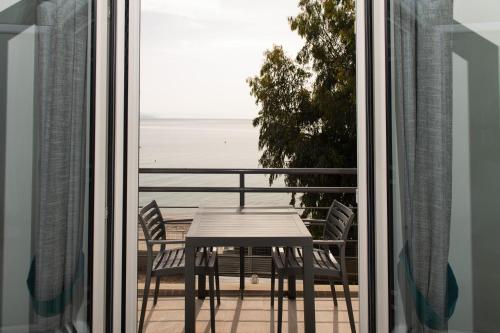 a table and chairs on a balcony with a view of the ocean at Loggos Apartments in Lóngos