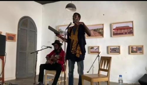 a man singing into a microphone next to a man holding a gun at Ndar Ndar House in Saint-Louis