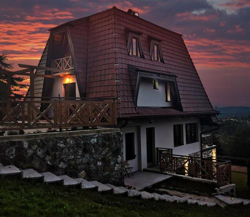 a house on a hill with a sunset in the background at KATUN Apartmani & SPA in Divčibare