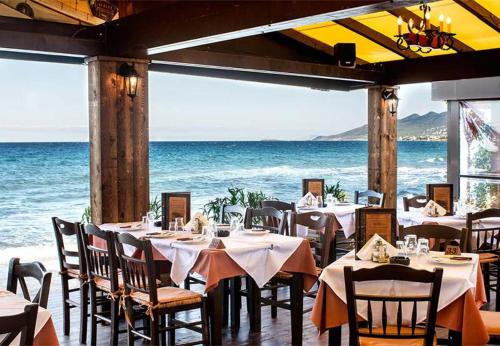 un restaurante con mesas y sillas y el océano en Georgias house 7 min from Athens airport, en Artemida