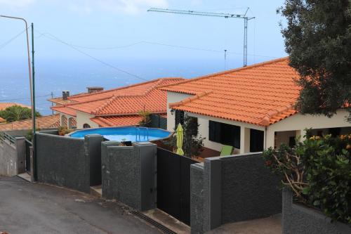 a house with an orange roof and a swimming pool at Suites Pinto Coelho in Caniço