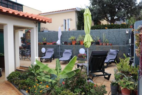 a patio with chairs and an umbrella and plants at Suites Pinto Coelho in Caniço