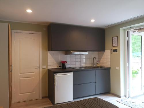 a kitchen with black cabinets and a white refrigerator at Atostogos Pervalkoje in Pervalka