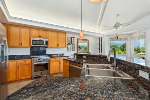 a kitchen with wooden cabinets and a sink at Villas of Kamalii 17 condo in Princeville