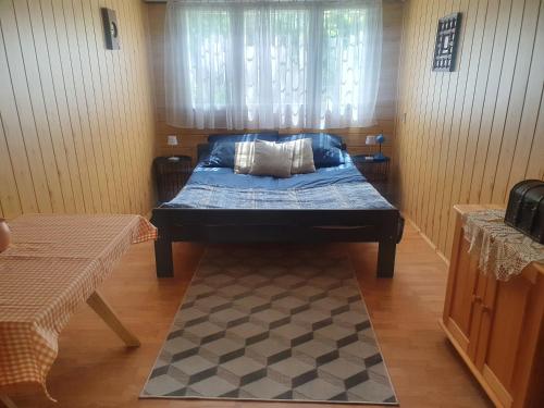 Ce lit se trouve dans un dortoir doté d'une fenêtre et d'un tapis. dans l'établissement Dwa prywatne domki letniskowe nad Jeziorem Łukcze, à Krasne Kosów