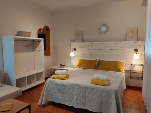Un dormitorio con una cama grande con almohadas amarillas. en ALOJAMIENTO La CAPILLITA HABITACION CON BAÑO, en Sanlúcar de Barrameda