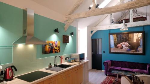 - une cuisine avec des murs bleus, un évier et un canapé dans l'établissement LE LOFT DE LA SALAMANDRE SARLAT, à Sarlat-la-Canéda