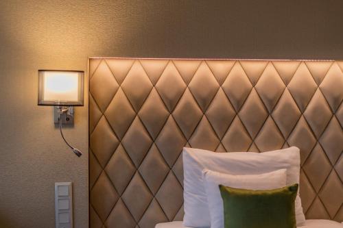 a headboard of a hotel room with a pillow and a lamp at Greenfield Hotel Golf & Spa in Bük