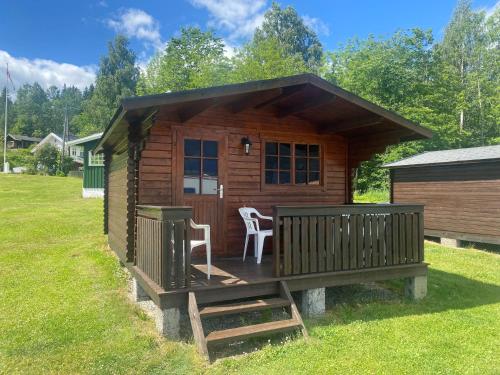 a cabin with a deck and a table and chairs at Garvikstrondi Camping in Seljord