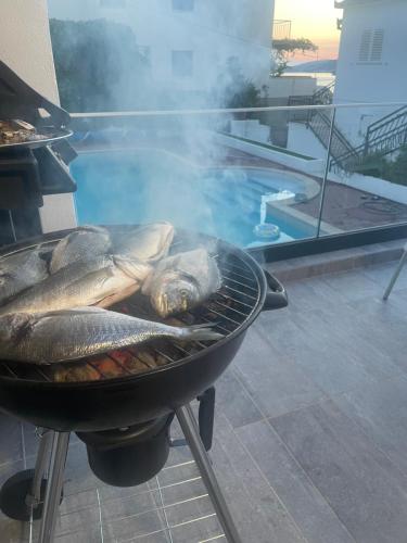 a fish is cooking on a grill next to a pool at Villa A'Mare in Seget Vranjica