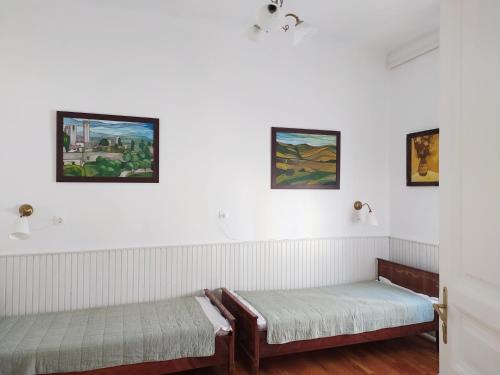two beds in a room with paintings on the wall at Atelier Keszthely Center in Keszthely