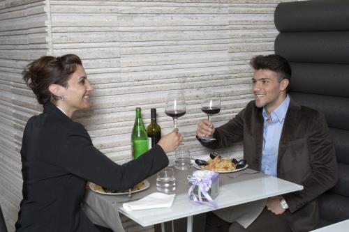 a man and woman sitting at a table with wine glasses at Hotel Briganti in Qualiano