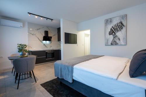 a bedroom with a bed and a table and a kitchen at Apartments & Room Forest in Slunj