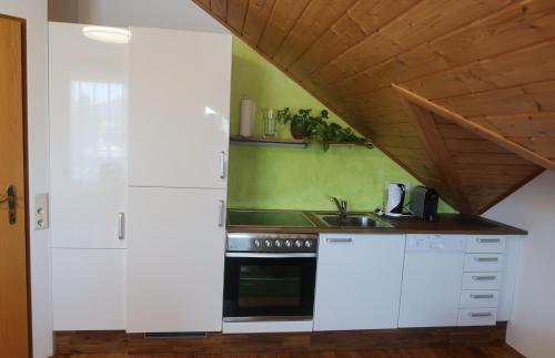 cocina con armarios blancos y techo de madera en Ferienwohnung Josy, en Sankt Kanzian