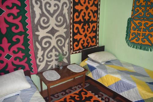 a room with two beds and a table and curtains at Guest House Oimo in Balykchy