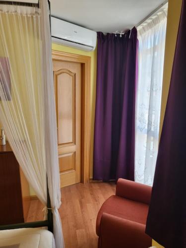 a living room with purple curtains and a red couch at Hotel Virginia R.H. in Vinuesa